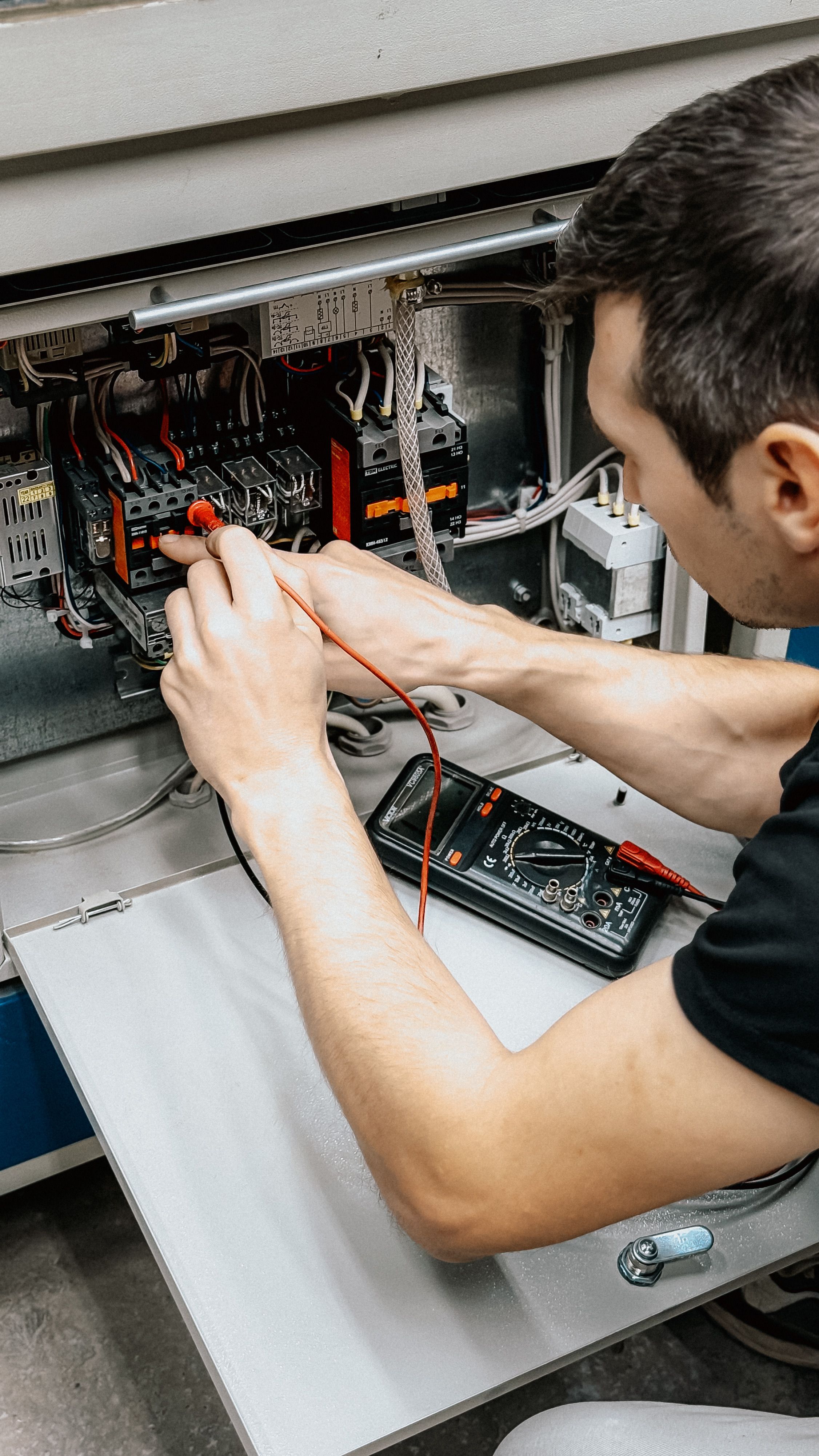 Electrician using a multimeter to diagnose an electrical panel