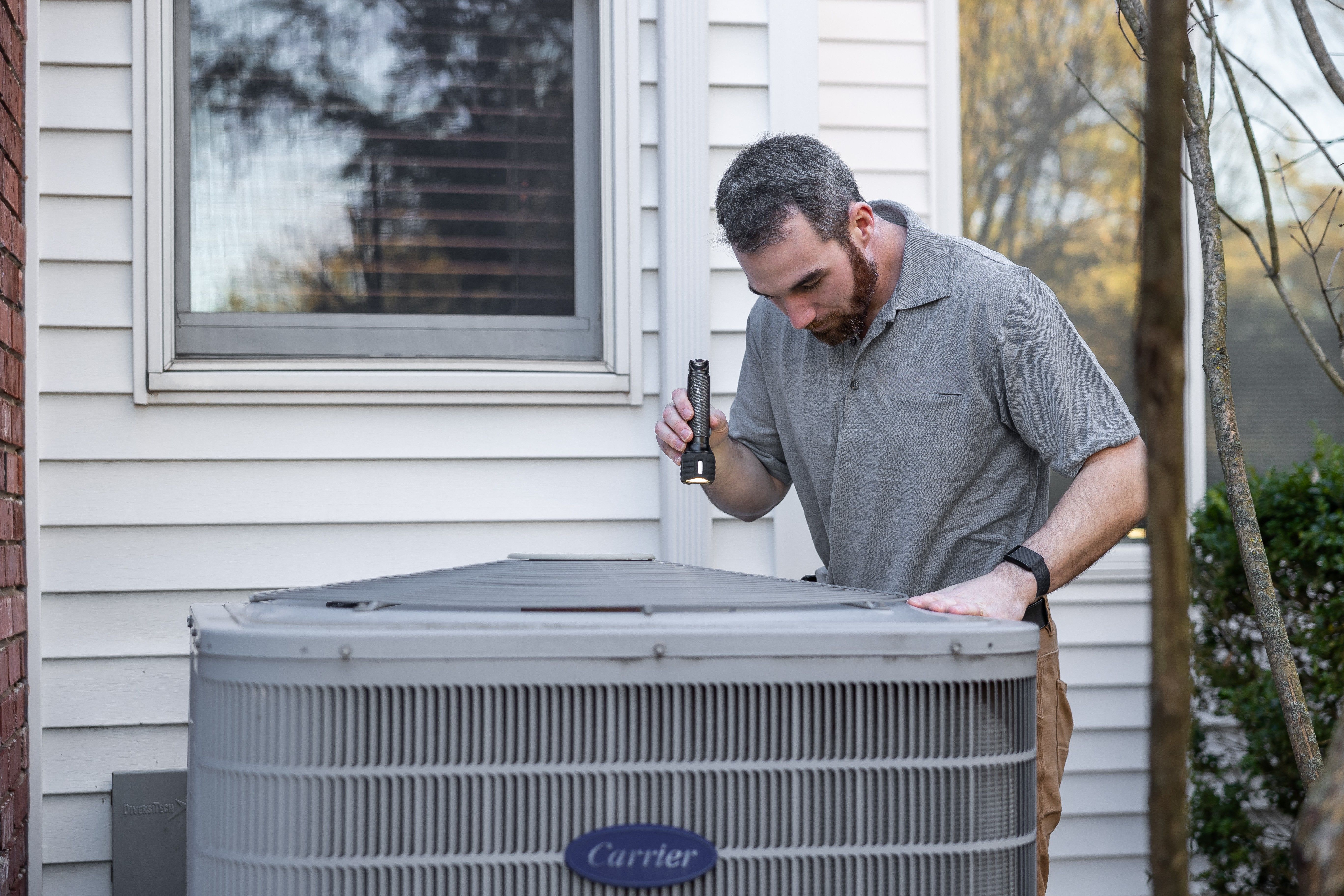 HVAC technician inspecting a residential outdoor air conditioning unit