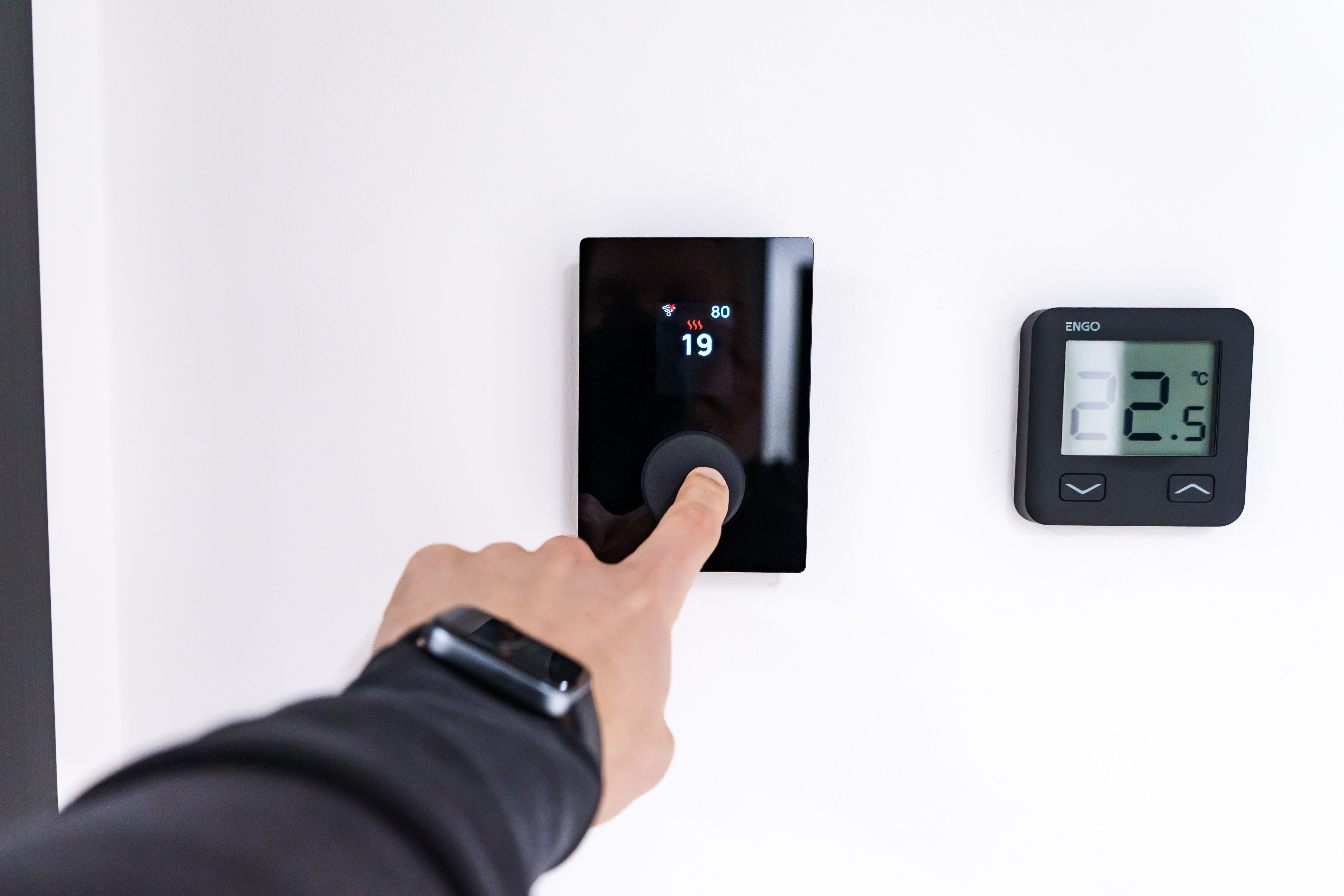Hand adjusting a modern digital thermostat