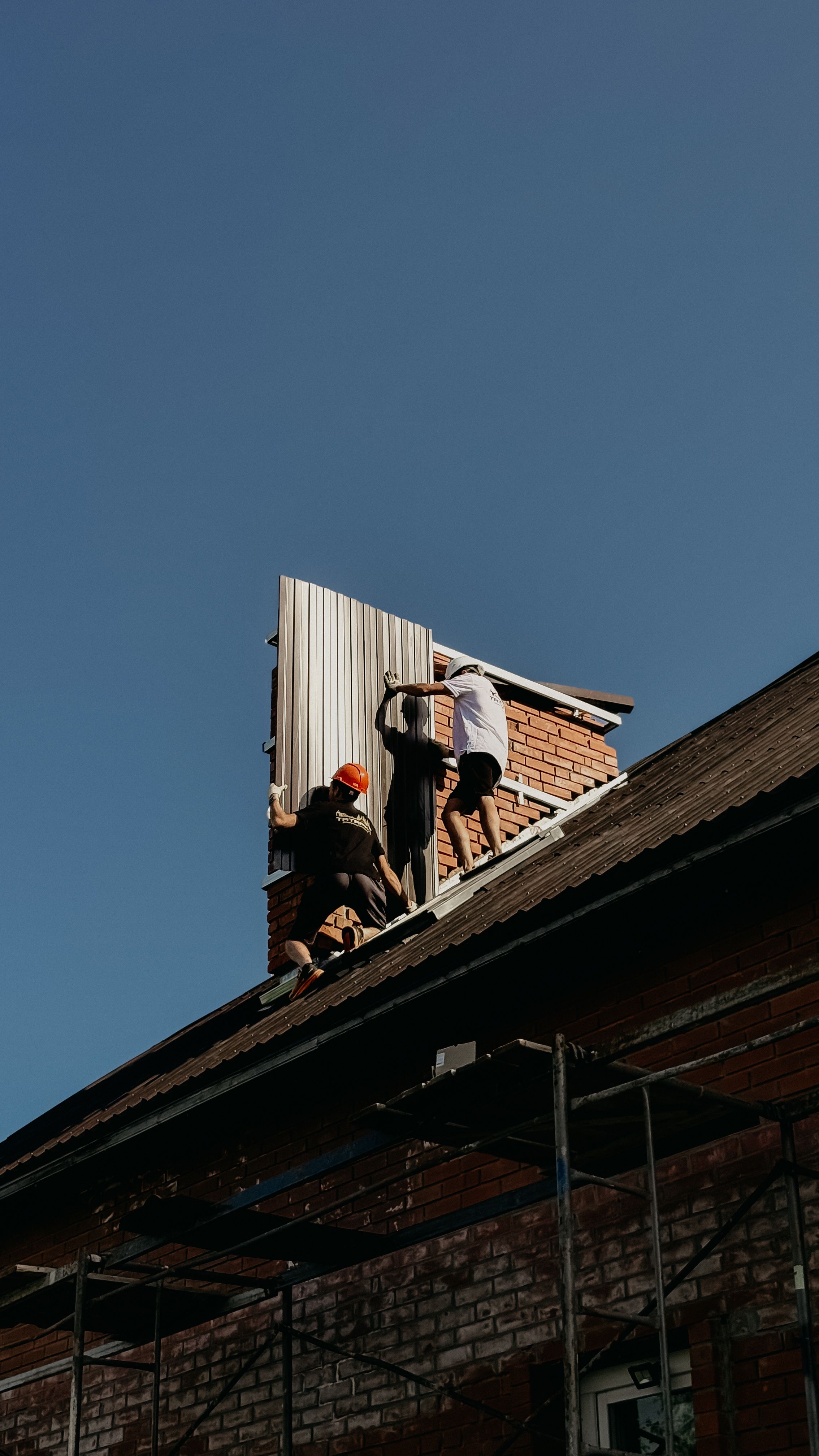 Roofing crew installing metal roof panels on a house