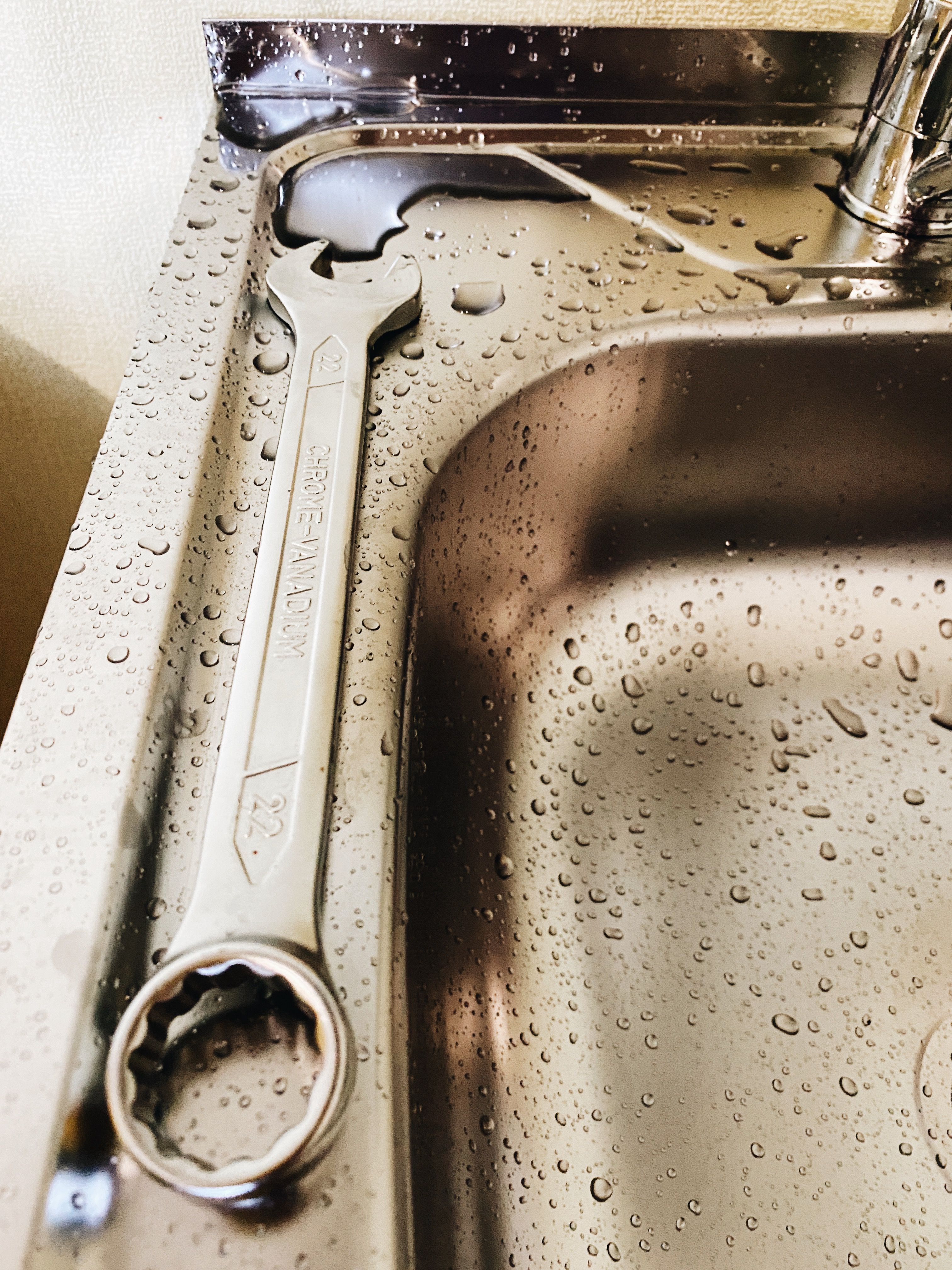 Plumbing wrench beside a wet sink