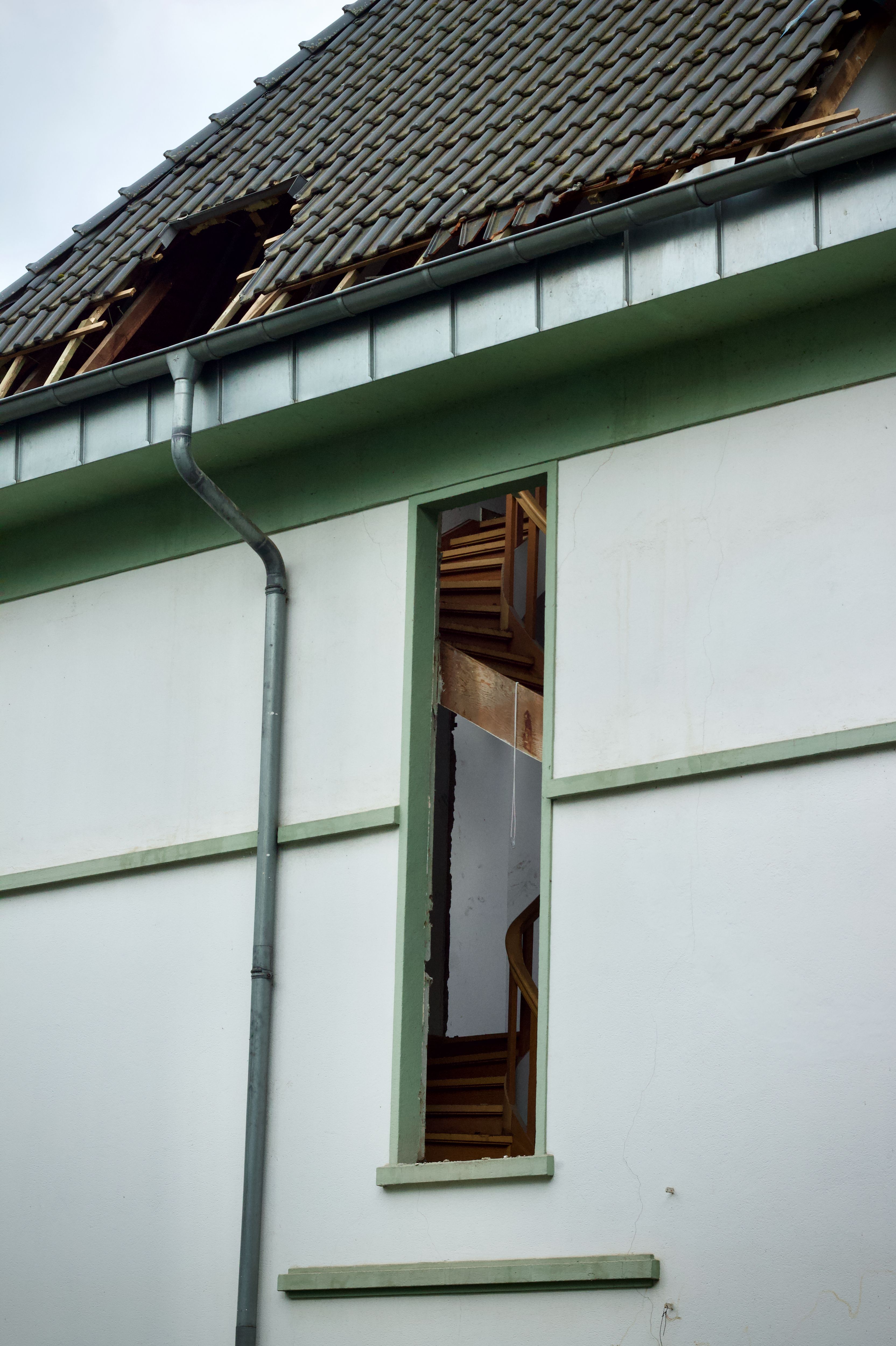 Residential house with serious roof damage and missing roofing materials